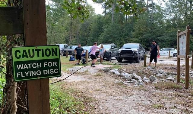 
			
				                                
			
				                                
			
				                                
			
				                                Photo courtesy Chris McDonald A sign reads ??  Attention: watch out for flying disks ??  tee off as a group of disc golfers at Hinson Lake.
 
			
		