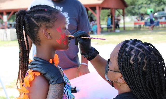  Dobbins Heights-native Dayona Johnson paints a constellation of hearts on the cheek of a young girl on Saturday. Gavin Stone | Daily Journal 