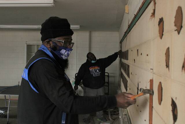 Bruce Stanback, volunteer director for the Cultural Center, left, and Councilman Maurice Stuart work to take down an aging chalk board on Saturday.
