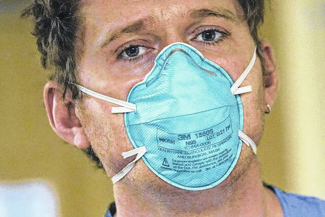 AP Photo | Elaine Thompson
                                Registered nurse Scott McGieson wears an N95 mask as he walks out of a patient’s room in the acute care unit of Harborview Medical Center, Friday, Jan. 14, 2022, in Seattle.